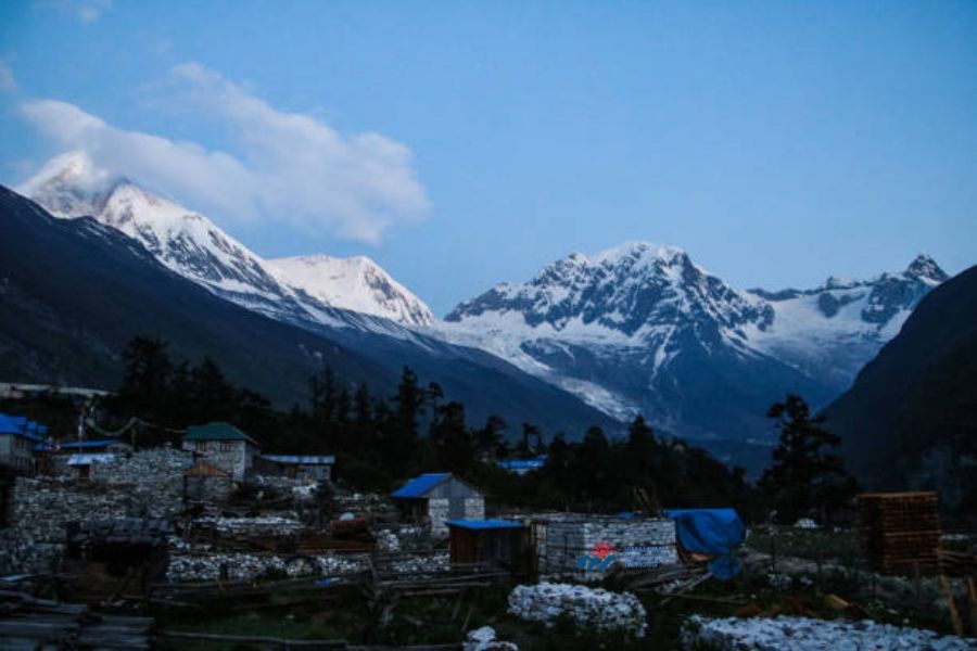 Himalayan village with traditional stone houses and glacier-covered mountains